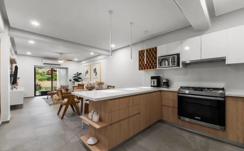 Cocina y comedor vistos desde la barra, con puertas corredizas de vidrio hacia el jardín al fondo