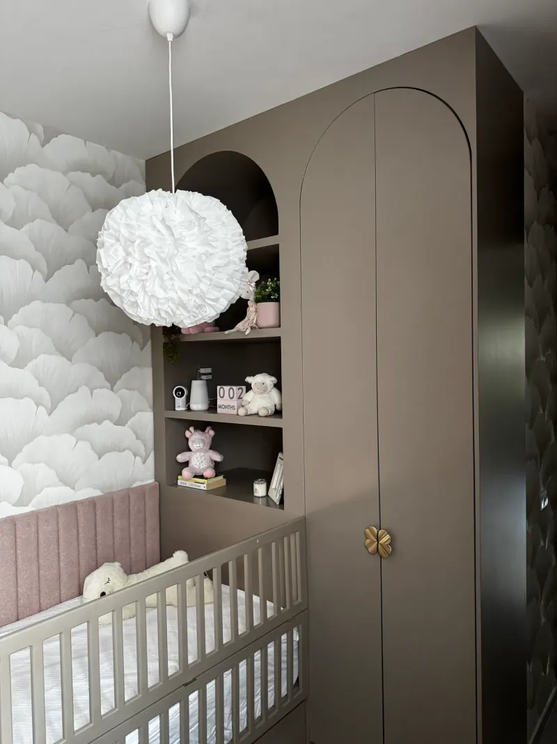 Mueble taupe de piso a techo con puertas en arco, perilla dorada en forma de flor y repisas con peluches