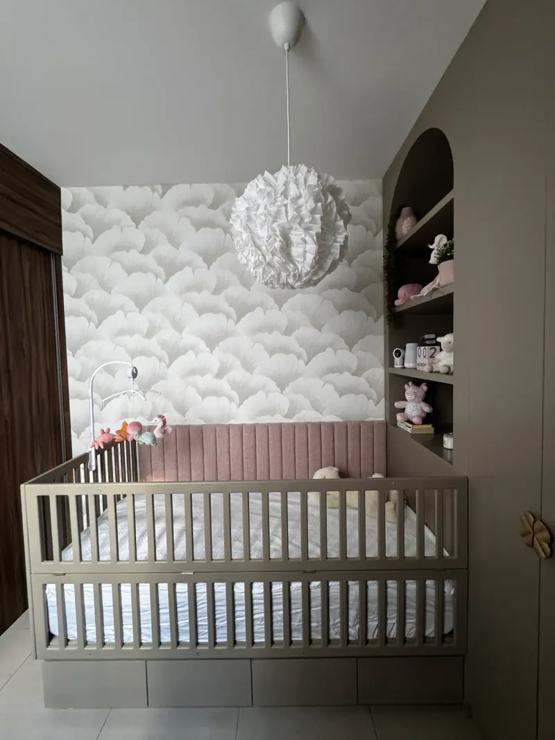 Nursery V, vista frontal de la cuna con base de frentes tipo cajón, panel acolchado rosa y lámpara de volantes blancos